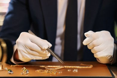 Photo of Appraiser working with luxury jewelry at table, closeup