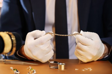 Photo of Appraiser working with luxury jewelry at table, closeup