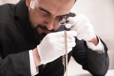 Photo of Appraiser evaluating luxury necklace indoors, closeup view