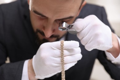 Photo of Appraiser evaluating luxury necklace indoors, closeup view