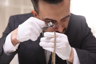 Photo of Appraiser evaluating luxury necklace indoors, closeup view