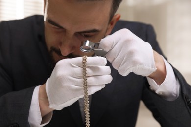 Photo of Appraiser evaluating luxury necklace indoors, closeup view