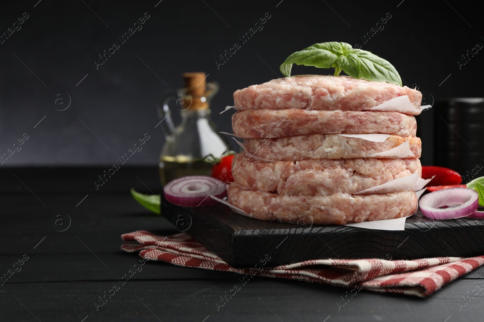 Fresh raw patties for burger and spices on black wooden table, closeup. Space for text Photo of Fresh raw patties for burger and spices on black wooden table, closeup. Space for text