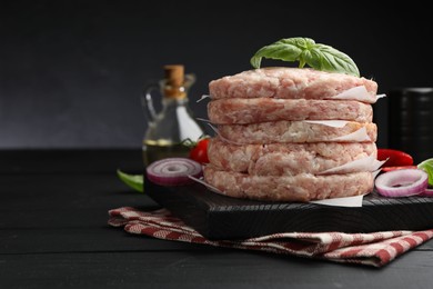 Photo of Fresh raw patties for burger and spices on black wooden table, closeup. Space for text