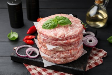 Photo of Fresh raw patties for burger and spices on black wooden table, closeup