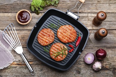 Photo of Delicious hamburger patties and spices on wooden table, flat lay