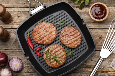 Photo of Delicious hamburger patties and spices on wooden table, flat lay