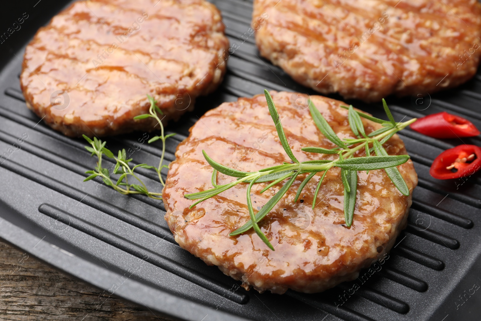Delicious hamburger patties and spices in frying pan on table, closeup Photo of Delicious hamburger patties and spices in frying pan on table, closeup