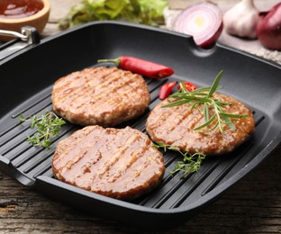 Photo of Delicious hamburger patties and spices on wooden table, closeup