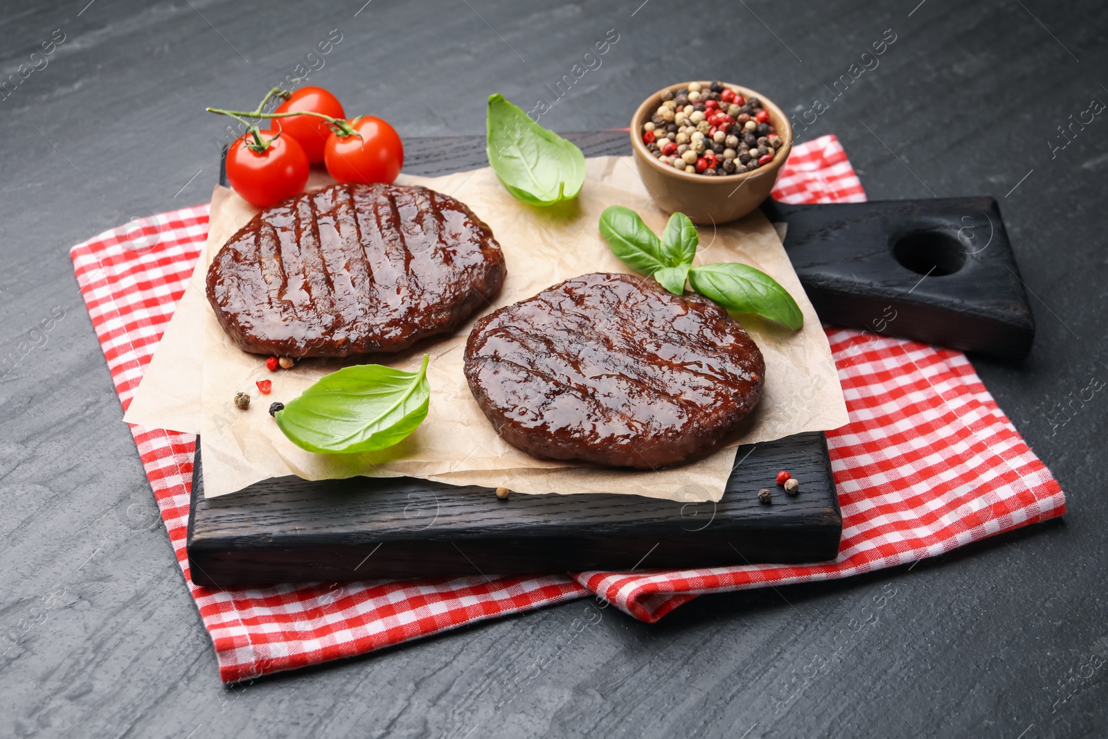 Delicious hamburger patties, tomatoes and spices on black table, closeup Photo of Delicious hamburger patties, tomatoes and spices on black table, closeup