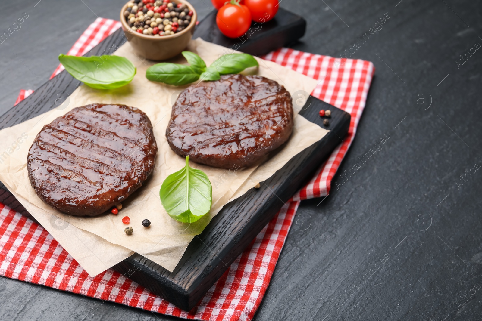 Delicious hamburger patties, tomatoes and spices on black table, closeup. Space for text Photo of Delicious hamburger patties, tomatoes and spices on black table, closeup. Space for text