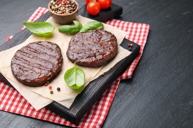 Photo of Delicious hamburger patties, tomatoes and spices on black table, closeup. Space for text