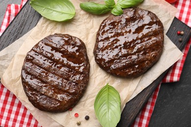 Photo of Delicious hamburger patties and spices on black table, top view