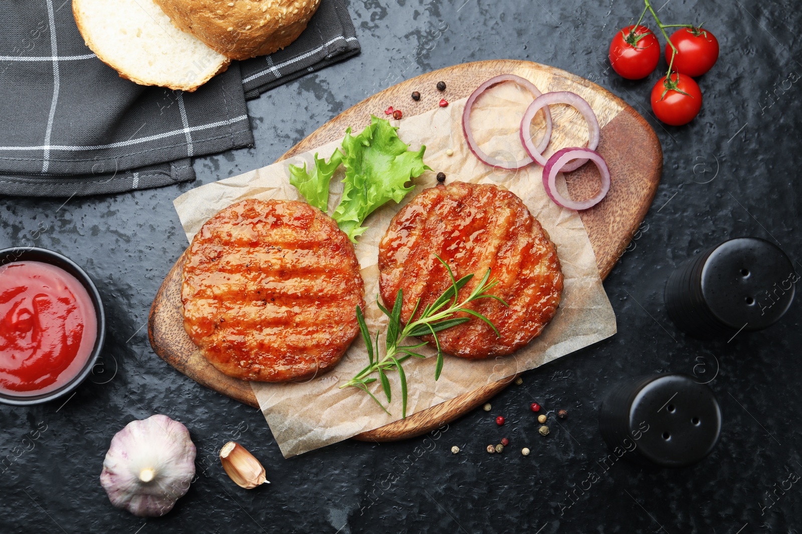Delicious hamburger patties, tomatoes and spices on black table, flat lay Photo of Delicious hamburger patties, tomatoes and spices on black table, flat lay