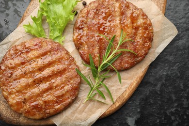 Photo of Delicious hamburger patties and spices on black table, top view