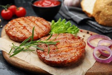 Photo of Delicious hamburger patties, tomatoes and spices on black table, closeup