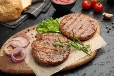 Photo of Delicious hamburger patties, tomatoes and spices on black table, closeup