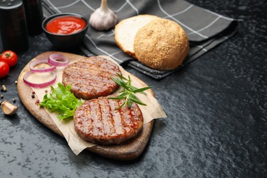 Photo of Delicious hamburger patties and spices on black table. Space for text