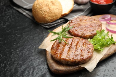 Photo of Delicious hamburger patties and spices on black table, closeup. Space for text