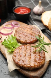 Photo of Delicious hamburger patties and spices on black table, closeup