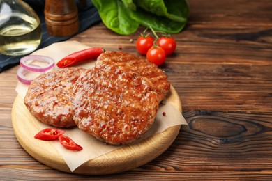 Photo of Delicious hamburger patties and spices on wooden table, closeup. Space for text