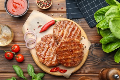 Photo of Delicious hamburger patties, tomatoes and spices on wooden table, flat lay