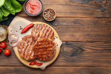 Photo of Delicious hamburger patties, tomatoes and spices on wooden table, flat lay. Space for text
