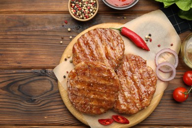 Photo of Delicious hamburger patties, tomatoes and spices on wooden table, flat lay. Space for text
