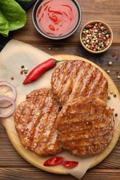 Photo of Delicious hamburger patties and spices on wooden table, flat lay