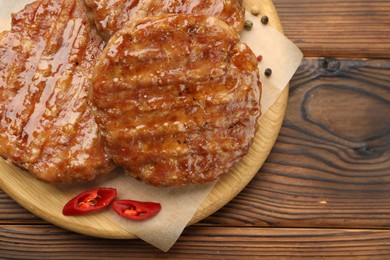 Photo of Delicious hamburger patties and spices on wooden table, top view. Space for text
