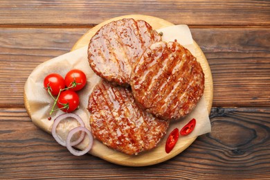 Photo of Delicious hamburger patties, tomatoes and spices on wooden table, top view