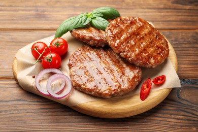 Photo of Delicious hamburger patties, tomatoes and spices on wooden table, closeup