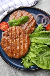 Photo of Delicious hamburger patties, tomato, lettuce and spices on grey table, top view