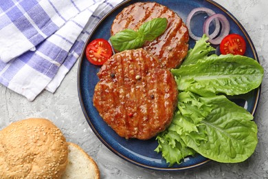 Photo of Delicious hamburger patties, tomato, lettuce, buns and spices on grey table, flat lay