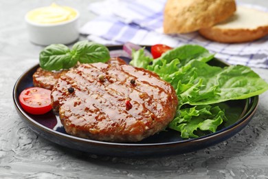 Photo of Delicious hamburger patties, tomato, lettuce, buns and spices on grey table, closeup