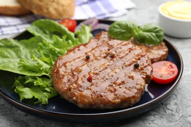 Photo of Delicious hamburger patties, tomato, lettuce and spices on grey table, closeup
