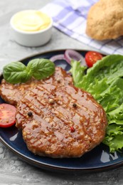 Photo of Delicious hamburger patties, tomato, lettuce and spices on grey table, closeup