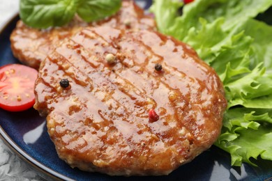Photo of Delicious hamburger patties, tomato, lettuce and spices on table, closeup