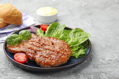 Photo of Delicious hamburger patties, tomato, lettuce, buns and spices on grey table, closeup. Space for text