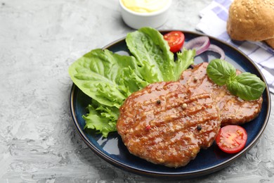 Photo of Delicious hamburger patties, tomato, lettuce, buns and spices on grey table, closeup. Space for text