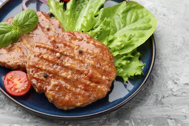 Photo of Delicious hamburger patties, tomato, lettuce and spices on grey table, closeup