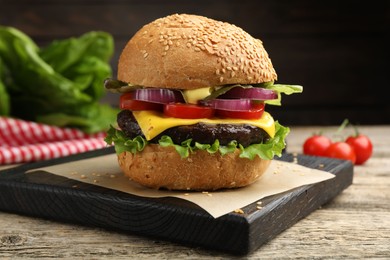 Photo of Delicious hamburger with patty and cheese on wooden table, closeup
