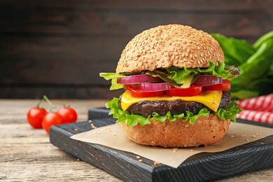Photo of Delicious hamburger with patty and cheese on wooden table, closeup. Space for text