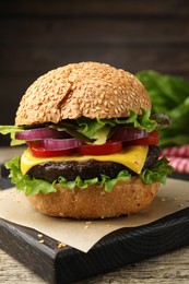 Photo of Delicious hamburger with patty and cheese on wooden table, closeup