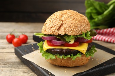 Photo of Delicious hamburger with patty and cheese on wooden table, closeup