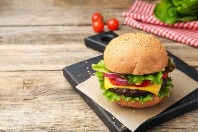 Photo of Delicious hamburger with patty and cheese on wooden table, closeup. Space for text