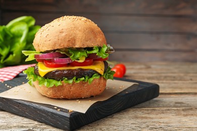 Photo of Delicious hamburger with patty and cheese on wooden table, closeup. Space for text