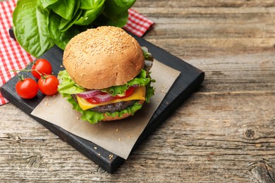 Photo of Delicious hamburger with patty and cheese on wooden table. Space for text