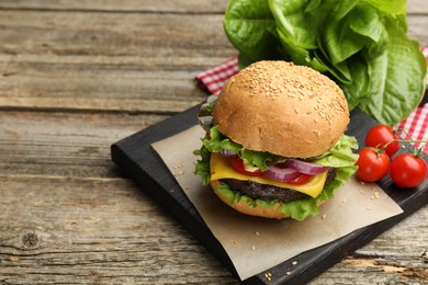 Photo of Delicious hamburger with patty and cheese on wooden table, closeup. Space for text