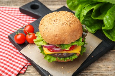 Photo of Delicious hamburger with patty and cheese on wooden table, closeup